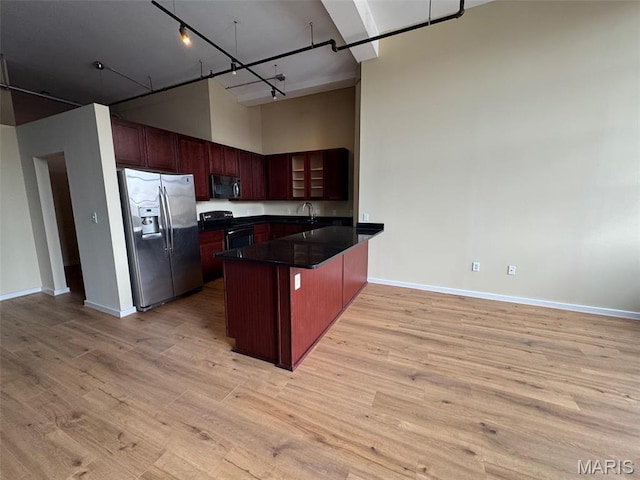 1520 Washington Ave Unit 617, Saint Louis, MO 63103 - kitchen with stainless steel fridge, black range with electric cooktop, dark countertops, a peninsula, and a towering ceiling