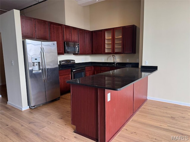 1520 Washington Ave Unit 617, Saint Louis, MO 63103 - kitchen with appliances with stainless steel finishes, a peninsula, light wood finished floors, glass insert cabinets, and dark stone countertops