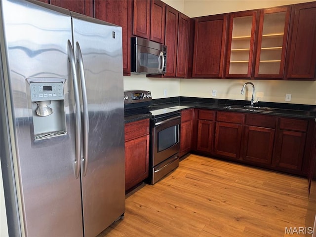 1520 Washington Ave Unit 617, Saint Louis, MO 63103 - kitchen featuring appliances with stainless steel finishes, dark brown cabinets, light wood-style floors, and glass insert cabinets