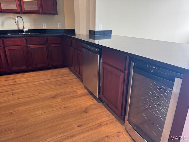 1520 Washington Ave Unit 617, Saint Louis, MO 63103 - kitchen with stainless steel dishwasher, beverage cooler, light wood-type flooring, and glass insert cabinets