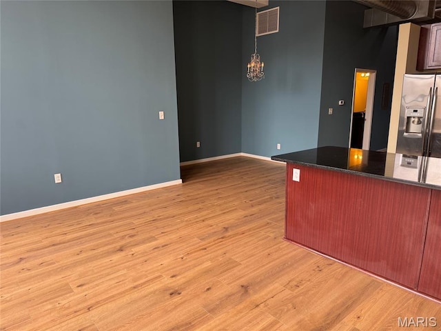 1520 Washington Ave Unit 617, Saint Louis, MO 63103 - kitchen featuring stainless steel fridge, light wood-style floors, a chandelier, dark stone countertops, and decorative light fixtures