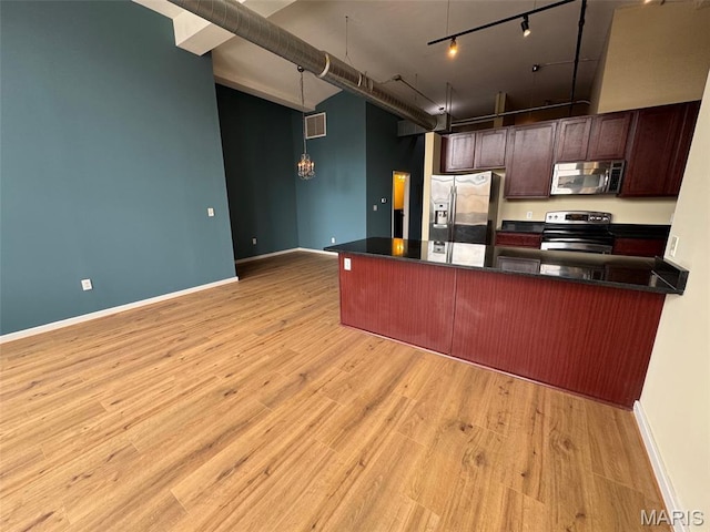 1520 Washington Ave Unit 617, Saint Louis, MO 63103 - kitchen featuring stainless steel appliances, dark countertops, rail lighting, light wood-style floors, and a peninsula