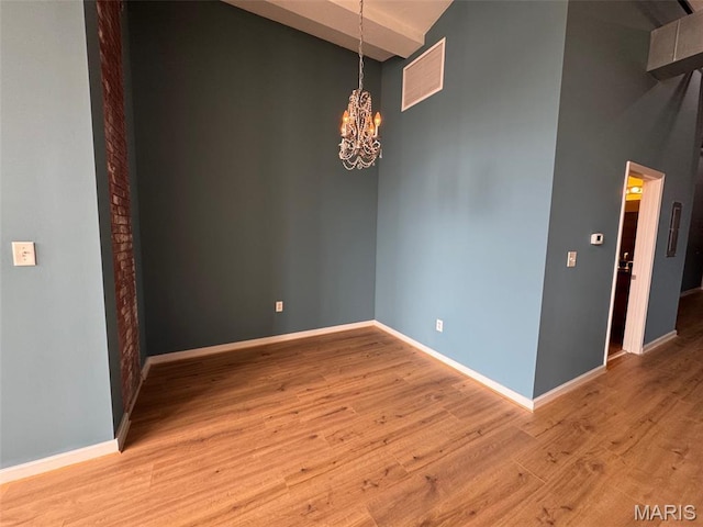 1520 Washington Ave Unit 617, Saint Louis, MO 63103 - empty room featuring a towering ceiling, a chandelier, light wood-type flooring, and beam ceiling