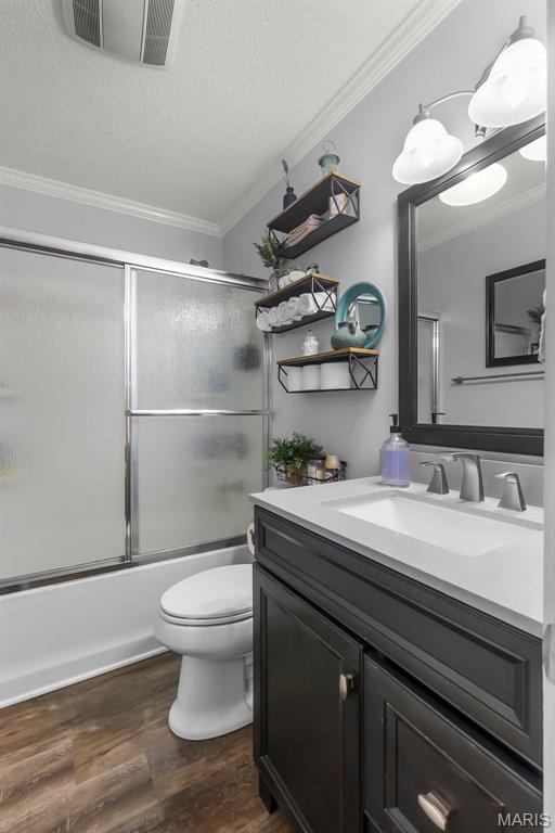 1004 Willow Ln, Sikeston, MO 63801 - bathroom featuring crown molding, vanity, shower / bath combination with glass door, wood finished floors, and a textured ceiling