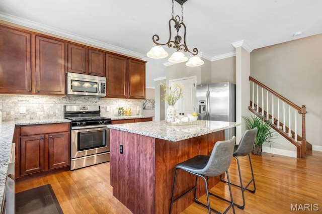 714 Oriental Lily Dr, Ofallon, MO 63366 - kitchen featuring appliances with stainless steel finishes, light wood-style floors, backsplash, ornamental molding, and a center island