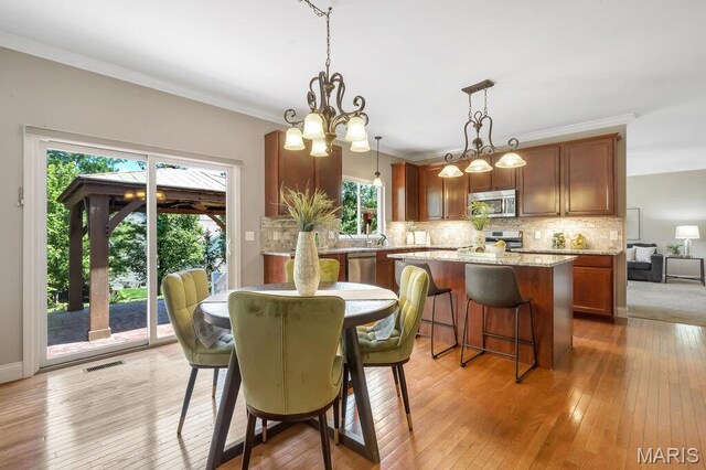 714 Oriental Lily Dr, Ofallon, MO 63366 - dining space featuring light wood-style flooring, crown molding, and a chandelier