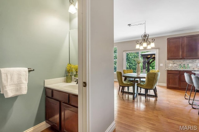 714 Oriental Lily Dr, Ofallon, MO 63366 - bathroom with vanity, wood finished floors, tasteful backsplash, crown molding, and a chandelier