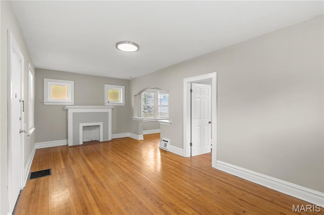 3800 Oakridge Blvd, Northwoods, MO 63121 - unfurnished living room with light wood-type flooring, arched walkways, and a fireplace with flush hearth