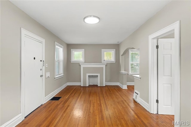3800 Oakridge Blvd, Northwoods, MO 63121 - unfurnished living room featuring light wood-style flooring, plenty of natural light, a fireplace, and arched walkways