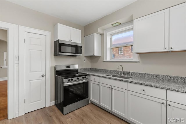3800 Oakridge Blvd, Northwoods, MO 63121 - kitchen with appliances with stainless steel finishes, light wood-style floors, white cabinets, and light stone counters