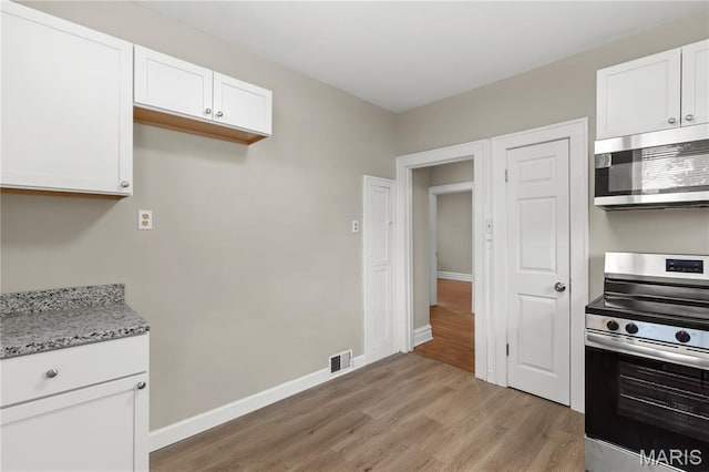 3800 Oakridge Blvd, Northwoods, MO 63121 - kitchen featuring appliances with stainless steel finishes, light wood-style flooring, white cabinets, and light stone countertops