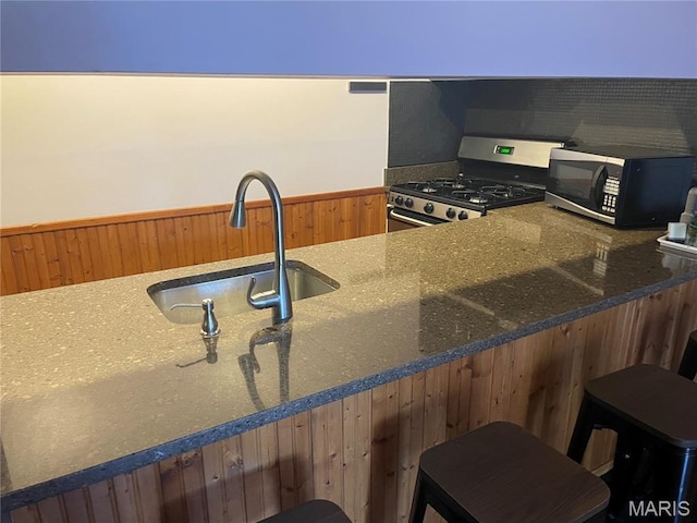 2319 Hickory St Unit A, Saint Louis, MO 63104 - kitchen with stainless steel range with gas cooktop, dark stone countertops, and a kitchen breakfast bar