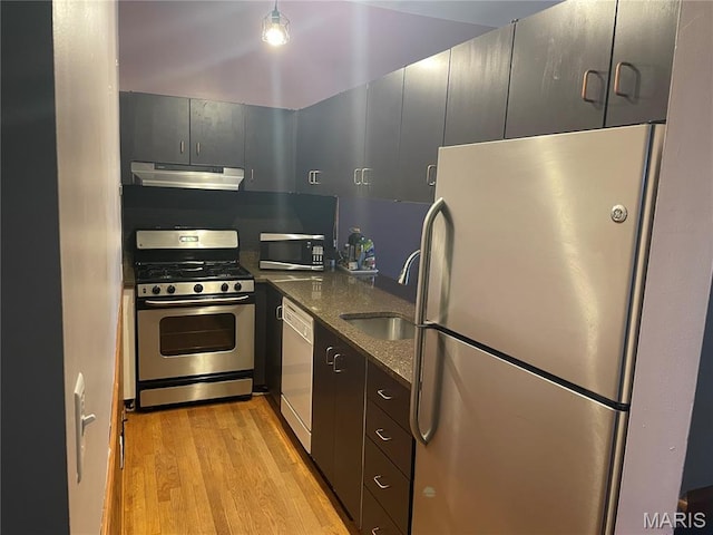 2319 Hickory St Unit A, Saint Louis, MO 63104 - kitchen with appliances with stainless steel finishes, under cabinet range hood, light wood finished floors, and dark stone counters