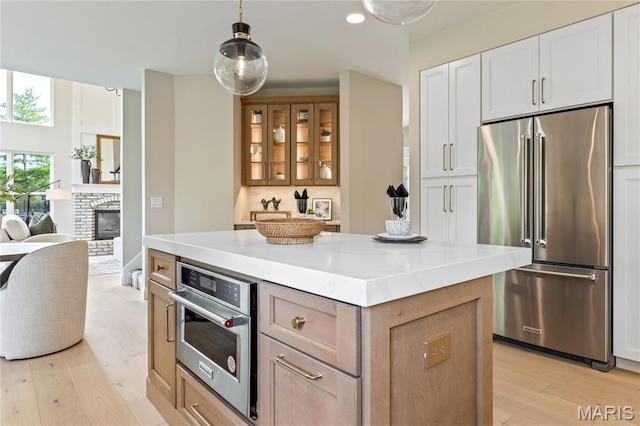 851 Whitmoor Dr, Weldon Spring, MO 63304 - kitchen with high end refrigerator, light wood-type flooring, a kitchen island, glass insert cabinets, and light countertops