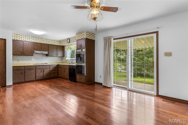 2844 Deborah Ann Dr, Arnold, MO 63010 - kitchen with under cabinet range hood, black appliances, light countertops, wood finished floors, and ceiling fan