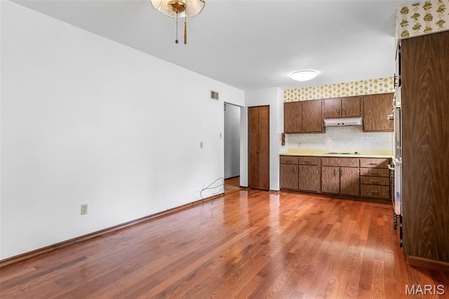 2844 Deborah Ann Dr, Arnold, MO 63010 - kitchen featuring wood finished floors, light countertops, under cabinet range hood, stovetop, and backsplash