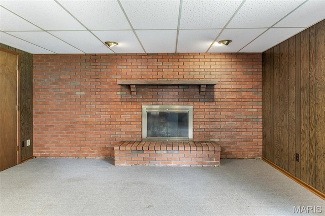 2844 Deborah Ann Dr, Arnold, MO 63010 - unfurnished living room featuring a drop ceiling, wooden walls, carpet floors, a brick fireplace, and brick wall