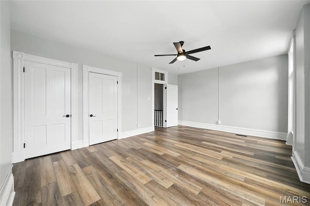 4550 Enright Ave, Saint Louis, MO 63108 - unfurnished bedroom featuring wood finished floors, a ceiling fan, and multiple closets