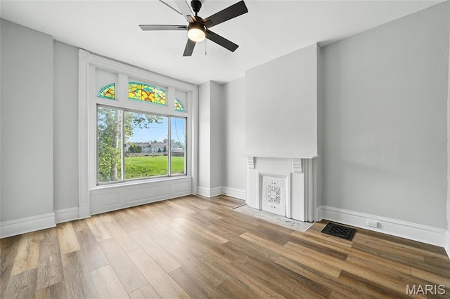 4550 Enright Ave, Saint Louis, MO 63108 - unfurnished living room featuring a ceiling fan, wood finished floors, and a fireplace with flush hearth