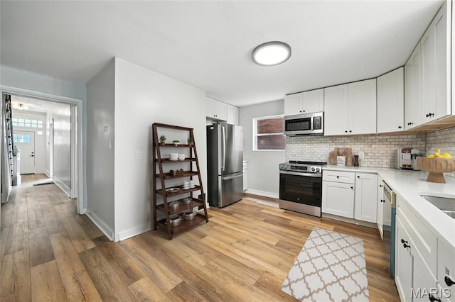 4550 Enright Ave, Saint Louis, MO 63108 - kitchen with stainless steel appliances, light countertops, decorative backsplash, and light wood-style floors