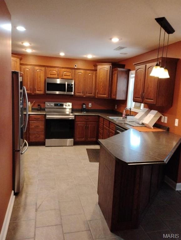 1107 Daffodil St, Sikeston, MO 63801 - kitchen with stainless steel appliances, a peninsula, brown cabinets, decorative light fixtures, and recessed lighting