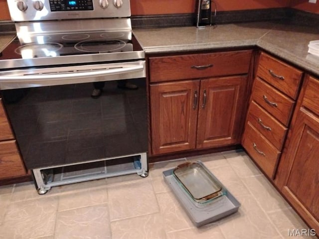 1107 Daffodil St, Sikeston, MO 63801 - kitchen with stainless steel electric range, brown cabinets, and light tile patterned floors