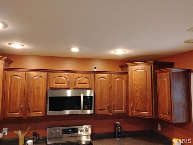 1107 Daffodil St, Sikeston, MO 63801 - kitchen featuring stainless steel microwave, stove, brown cabinetry, recessed lighting, and dark countertops