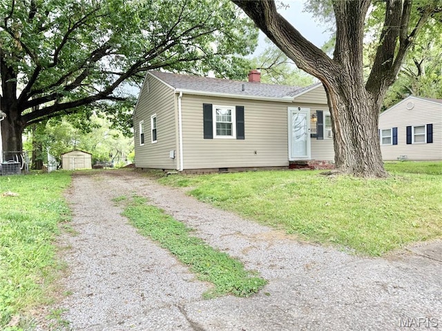 3212 Rodger Ave, Granite City, IL 62040 - view of front facade with a storage shed, a chimney, a shingled roof, and a front lawn