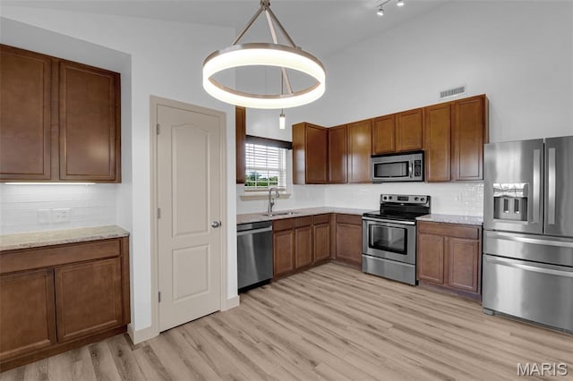 1531 Piedmont Cir Unit 1531, Saint Peters, MO 63304 - kitchen featuring stainless steel appliances, light wood finished floors, decorative backsplash, brown cabinetry, and a high ceiling