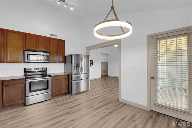 1531 Piedmont Cir Unit 1531, Saint Peters, MO 63304 - kitchen with stainless steel appliances, tasteful backsplash, light wood-type flooring, brown cabinets, and a high ceiling