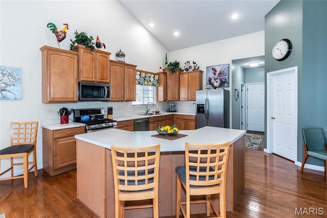 221 Meriwether Lewis Dr, Ofallon, MO 63368 - kitchen featuring appliances with stainless steel finishes, high vaulted ceiling, dark wood-style floors, a breakfast bar area, and a center island