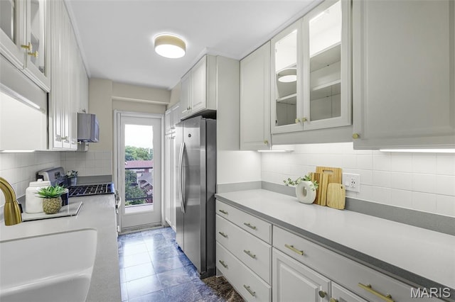 4466 W Pine Blvd Unit 7D, Saint Louis, MO 63108 - kitchen featuring freestanding refrigerator, decorative backsplash, white cabinets, and light countertops