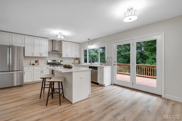 1254 Jade Wind Cir, Ballwin, MO 63011 - kitchen featuring stainless steel appliances, wall chimney exhaust hood, tasteful backsplash, light countertops, and white cabinetry