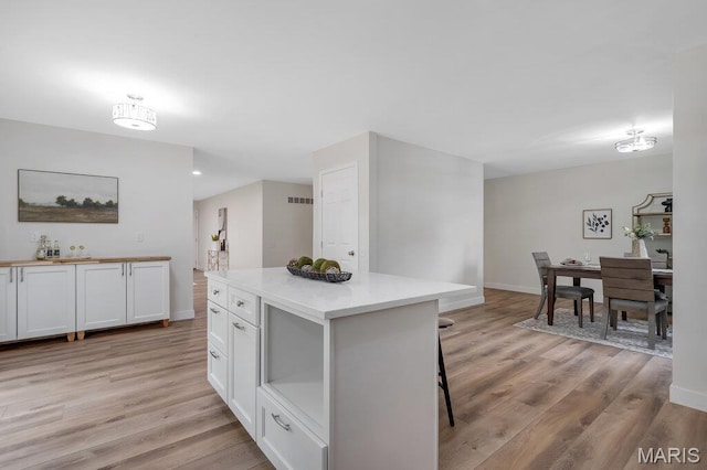1254 Jade Wind Cir, Ballwin, MO 63011 - kitchen with white cabinetry, light wood finished floors, a kitchen breakfast bar, and a kitchen island