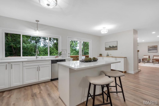 1254 Jade Wind Cir, Ballwin, MO 63011 - kitchen featuring stainless steel dishwasher, light countertops, a breakfast bar, light wood finished floors, and white cabinetry