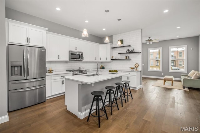 3400 Vista Ave, Saint Louis, MO 63104 - kitchen with stainless steel appliances, open shelves, decorative backsplash, a breakfast bar, and white cabinets