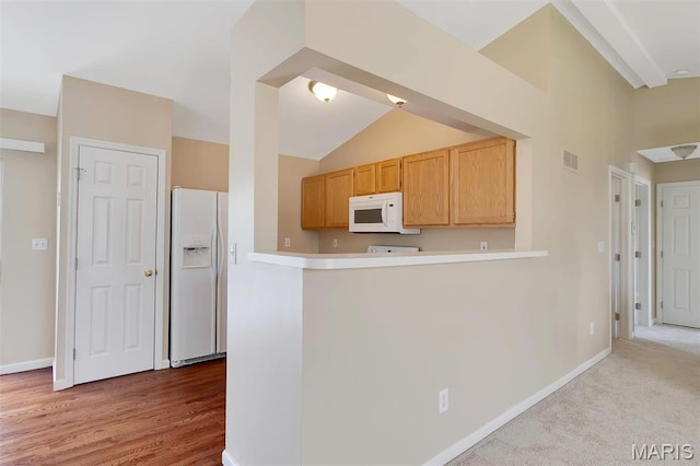 536 White Fence Dr, Wentzville, MO 63385 - kitchen featuring white appliances, vaulted ceiling, light countertops, a peninsula, and light wood-type flooring