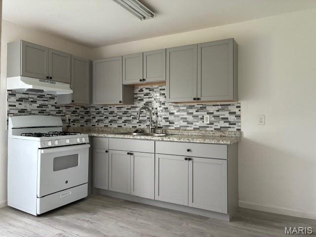 515 N 37th St, Belleville, IL 62226 - kitchen with white range with gas stovetop, under cabinet range hood, gray cabinets, and backsplash