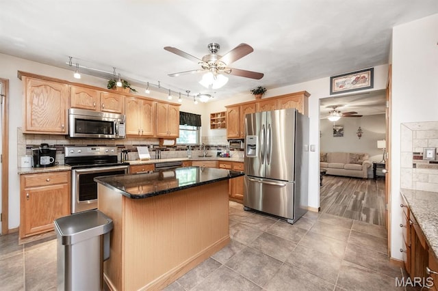 595 Chancellor Dr, Edwardsville, IL 62025 - kitchen featuring appliances with stainless steel finishes, ceiling fan, decorative backsplash, a center island, and dark stone countertops