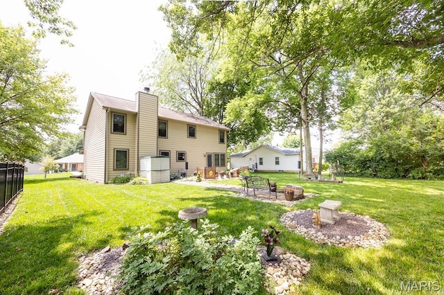 595 Chancellor Dr, Edwardsville, IL 62025 - rear view of property featuring an outdoor fire pit, a chimney, and a lawn