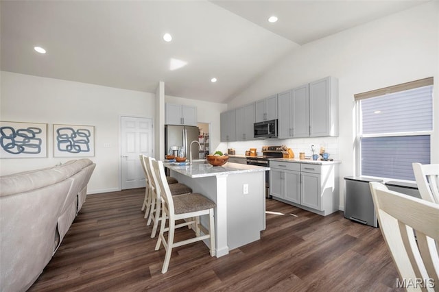 155 Pampano Ln, Saint Charles, MO 63301 - kitchen featuring stainless steel appliances, lofted ceiling, a breakfast bar area, dark wood finished floors, and decorative backsplash