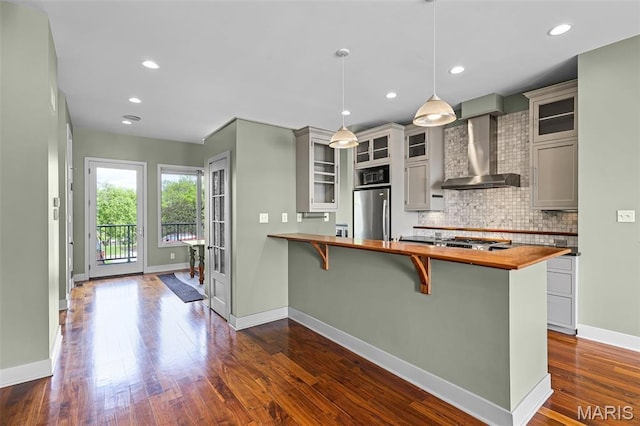 5310 Chouteaus Bluff Dr Unit 5310, Saint Louis, MO 63111 - kitchen featuring wall chimney range hood, butcher block counters, freestanding refrigerator, tasteful backsplash, and a breakfast bar area