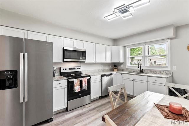 1140 Lindsay Ln, Florissant, MO 63031 - kitchen featuring stainless steel appliances, light wood finished floors, white cabinetry, and light stone counters