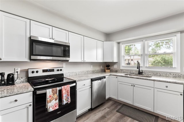1140 Lindsay Ln, Florissant, MO 63031 - kitchen with stainless steel appliances, light wood-type flooring, and white cabinetry