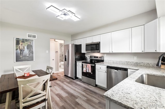 1140 Lindsay Ln, Florissant, MO 63031 - kitchen featuring appliances with stainless steel finishes, light stone counters, and white cabinetry