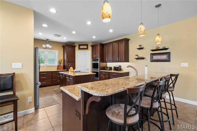 108 Jennings Ln, Sikeston, MO 63801 - kitchen featuring stainless steel appliances, a center island with sink, dark brown cabinetry, a breakfast bar, and a peninsula