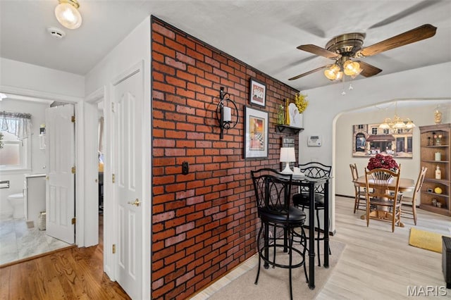 111 Freedom Dr, Belleville, IL 62226 - dining area with brick wall, wood finished floors, a ceiling fan, a chandelier, and arched walkways