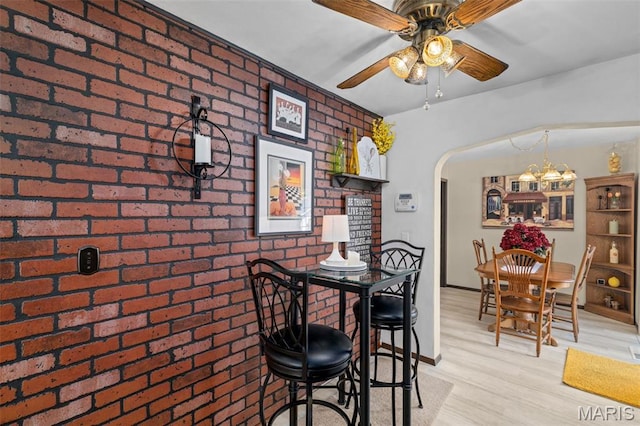111 Freedom Dr, Belleville, IL 62226 - dining space featuring brick wall, arched walkways, a ceiling fan, a chandelier, and light wood finished floors