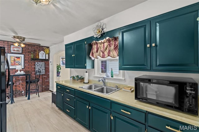 111 Freedom Dr, Belleville, IL 62226 - kitchen with black appliances, light countertops, brick wall, ceiling fan, and light wood-type flooring