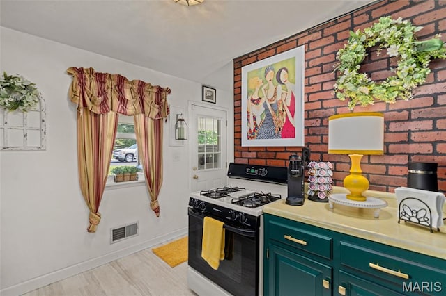 111 Freedom Dr, Belleville, IL 62226 - kitchen featuring gas range, green cabinetry, light countertops, and brick wall